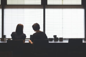 Two Japanese businesswomen working together with laptops, in modern business shared casual working area.