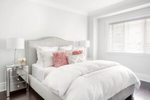 Horizontal image of bright guest bedroom, with suede headboard and matching side tables and lamps.