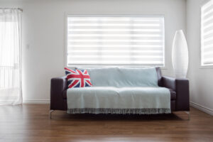 Horizontal image of  a modern leather sofa with throw and a Union Jack pillow, in bright living room. Space for copy.