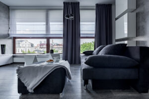 Contemporary living room with gray couch, pouf and big windows